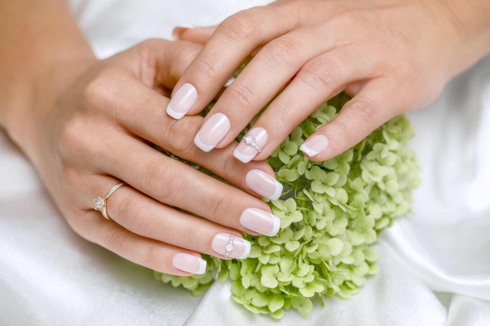 Beautiful French manicure in pink and white with rhinestones for the bride. Close-up nails. Wedding accessories